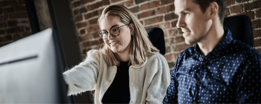 Two colleagues collaborating at a computer, creating on-brand content using Papirfly's tools